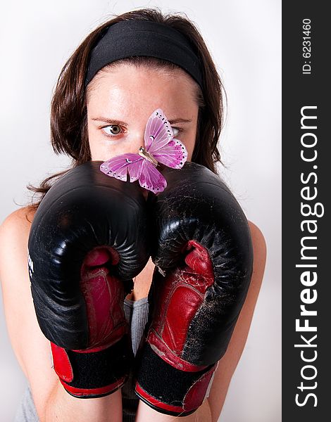 Boxing young women with butterfly on light background