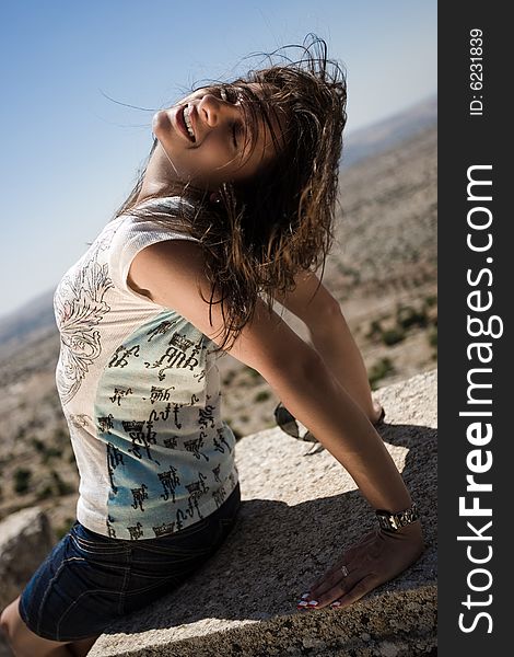 Girl with brown hair is sitting on the stone. Girl with brown hair is sitting on the stone