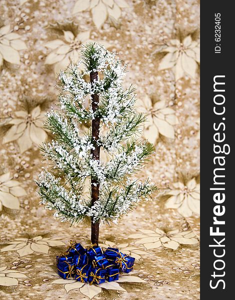 Evergreen tree with white snow, blue presents underneath, and against a background of white/gold poinsettia. Evergreen tree with white snow, blue presents underneath, and against a background of white/gold poinsettia.