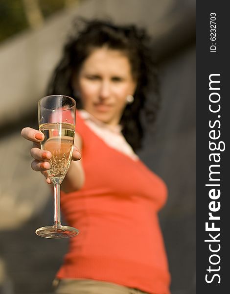 Outdoor portrait of woman with champagne glass, focus on glass