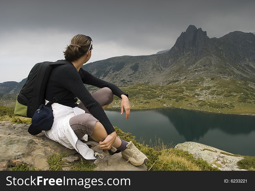 Resting mountaineer sitting on a rock. The picture was taken on the Seven Rila lakes in the Rila mountain, Bulgaria.
