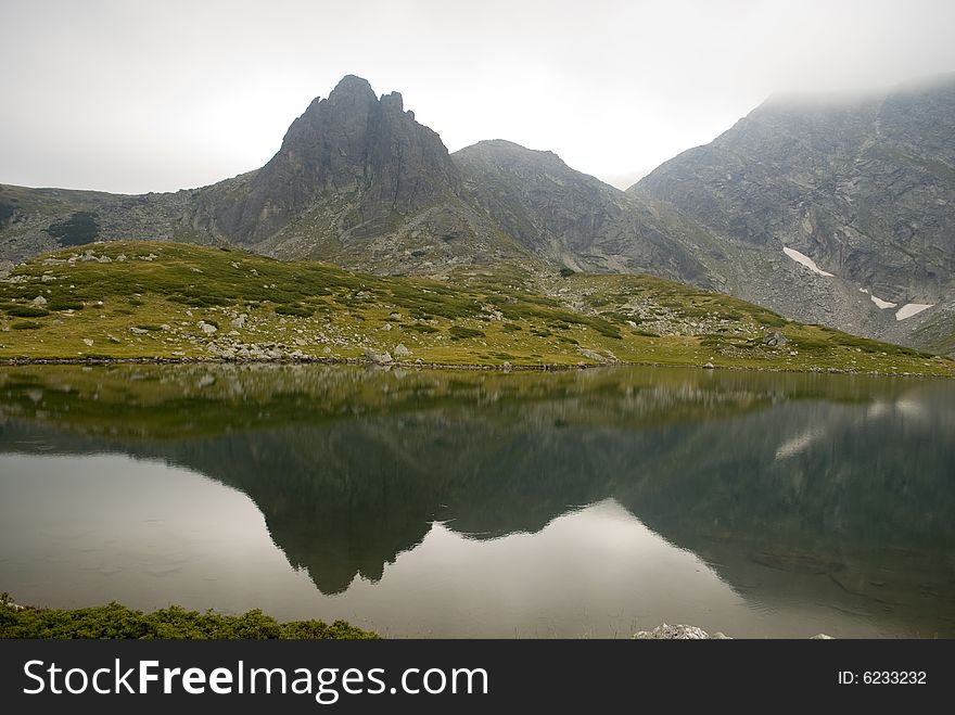 Beautiful highland lake and vast mountain on a cloudy day. The picture was taken on the Seven Rila lakes (above 2200m.) in Rila mountain, Bulgaria. Beautiful highland lake and vast mountain on a cloudy day. The picture was taken on the Seven Rila lakes (above 2200m.) in Rila mountain, Bulgaria.