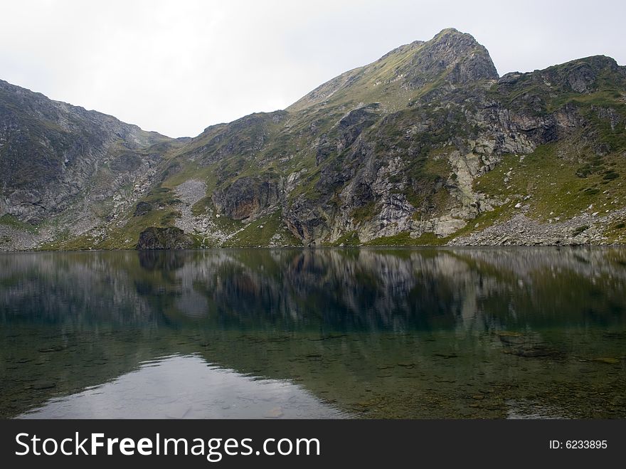 Beautiful highland lake and vast mountain on a cloudy day. The picture was taken on the Seven Rila lakes (above 2200m.) in Rila mountain, Bulgaria.