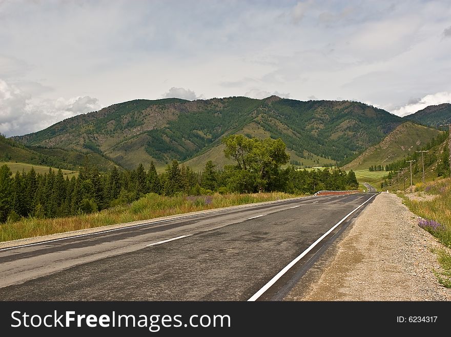 Straight asphalt road from left to right in mountains. Straight asphalt road from left to right in mountains