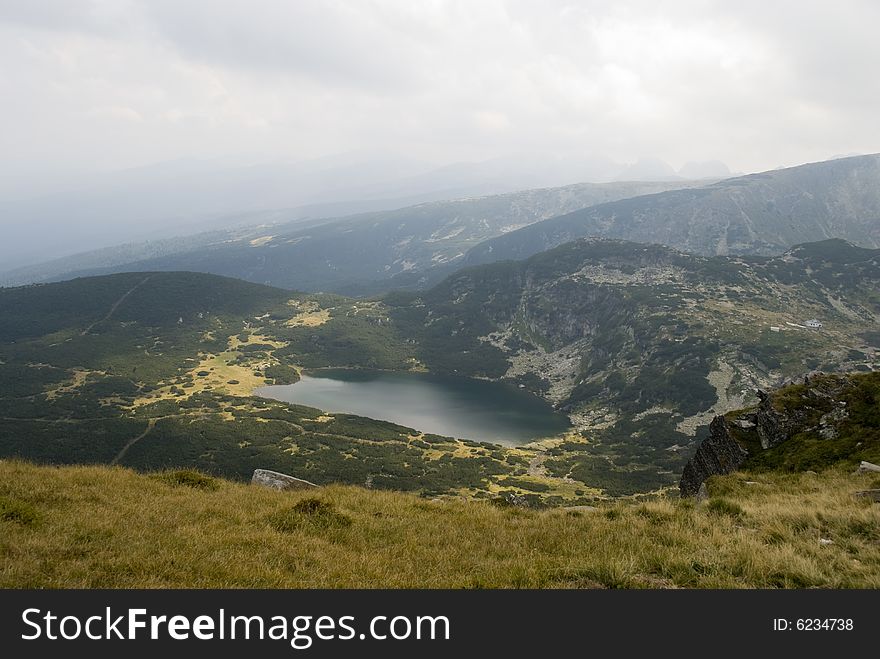 Beautiful highland lake and vast mountain on a cloudy day. The picture was taken on the Seven Rila lakes (above 2200m.) in Rila mountain, Bulgaria.