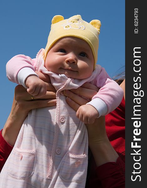 Little baby on mother's hands on blue sky background