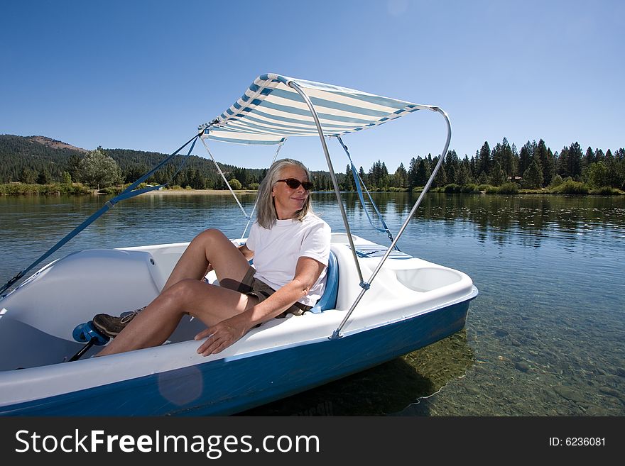 Senior woman in paddle boat on pond. Senior woman in paddle boat on pond