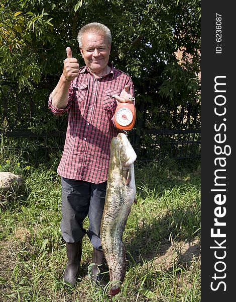 Happy and proud fisher demonstrates catched cat fish of 7 kilo weight. Happy and proud fisher demonstrates catched cat fish of 7 kilo weight