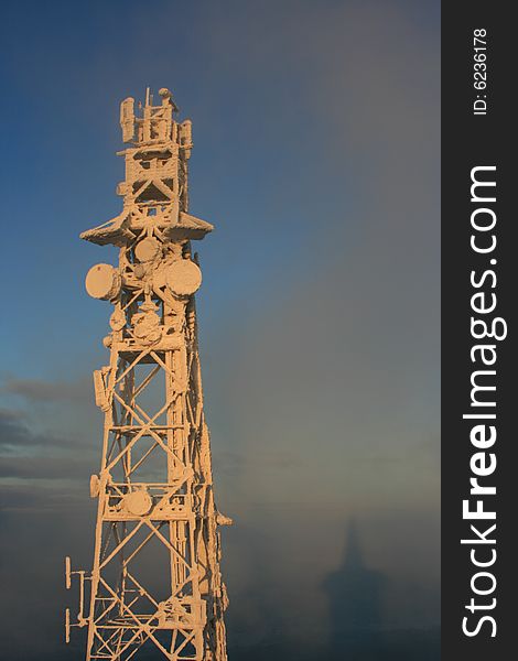 Antenna mast on Jedlova Hill, Czech Republic. Shadow of observation tower on clouds is in lower right corner.