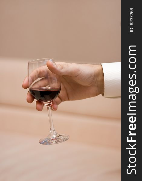 Man's hand keeps a glass with a red wine on light background