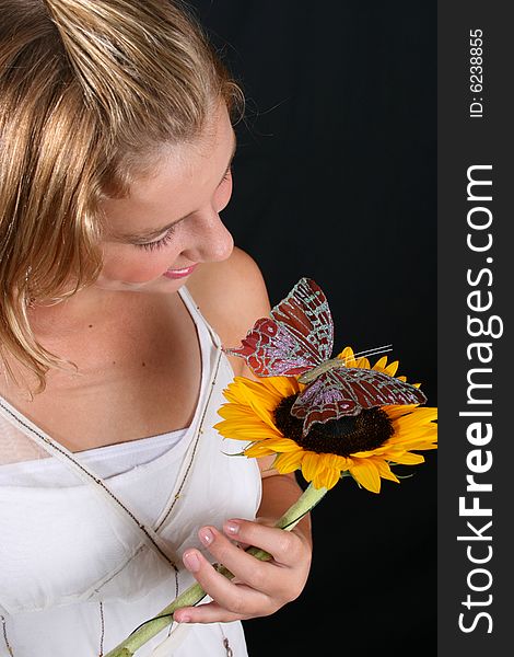 Teenage female model holding a sunflower with a butterfly. Teenage female model holding a sunflower with a butterfly