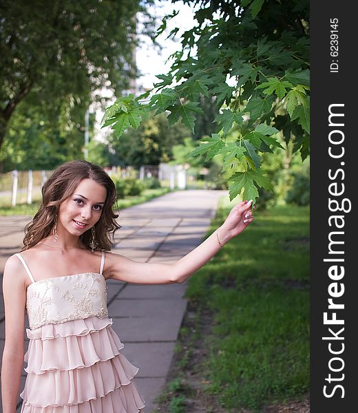 Girl teenager stands outdoor and touches leaf of maple. Girl teenager stands outdoor and touches leaf of maple.