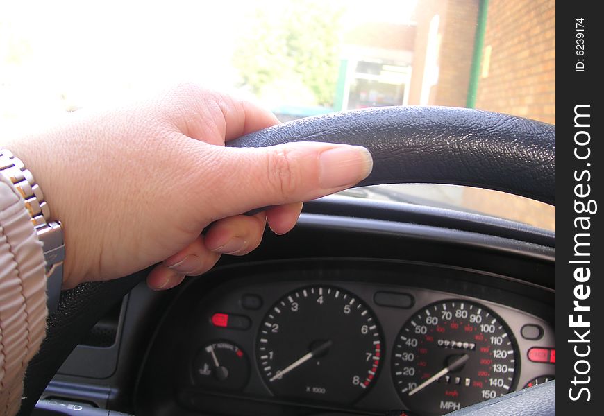 Left hand on the steering wheel of a car. Left hand on the steering wheel of a car