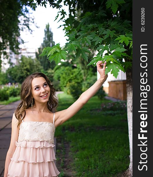 Girl teenager stands outdoor and touches leaf of maple. Girl teenager stands outdoor and touches leaf of maple.