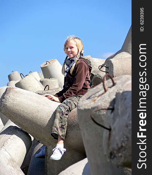 Young blond girl siting on the breakwater. Young blond girl siting on the breakwater.