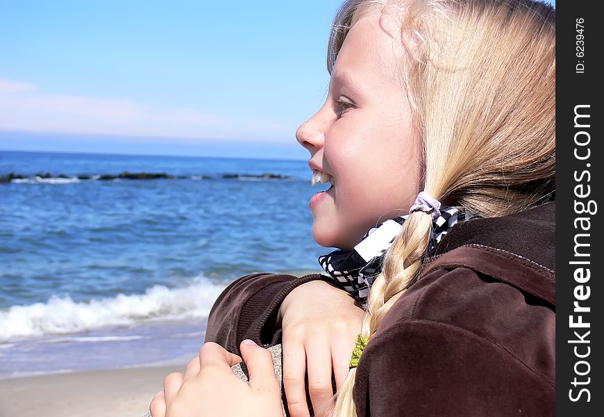 Young blond girl smiling at seaside - close up