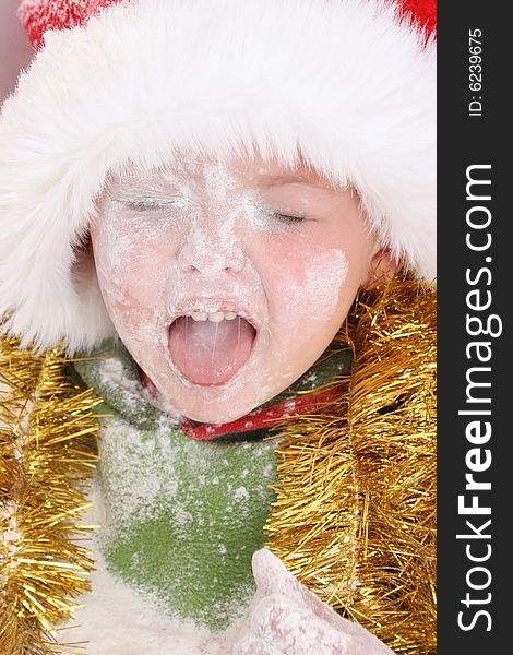 Toddler wearing a christmas hat, covered in flour. Toddler wearing a christmas hat, covered in flour