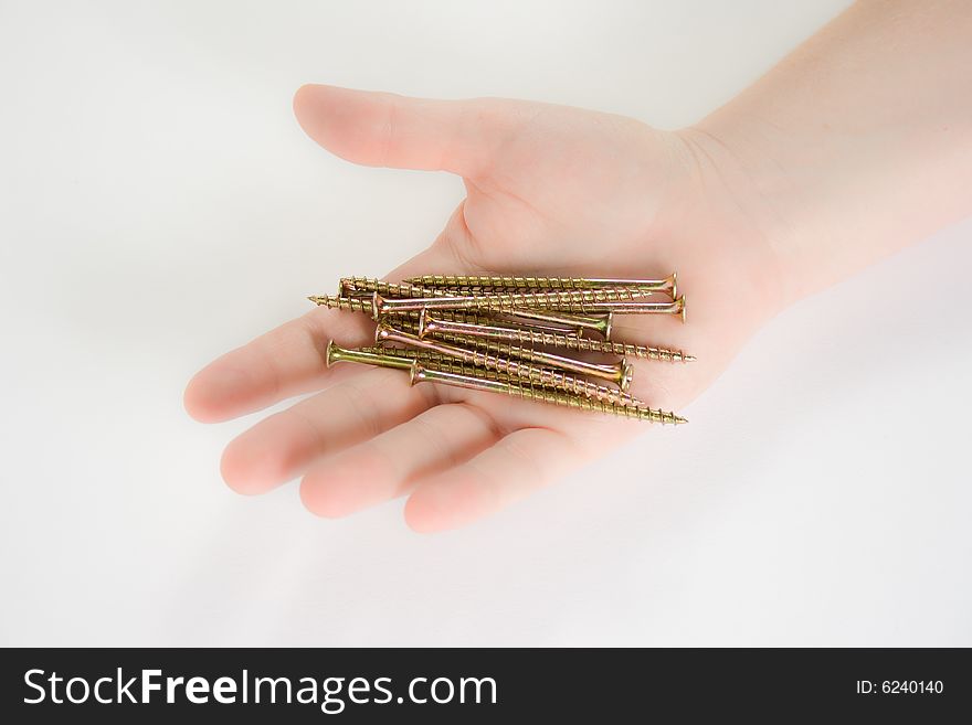 A hand holding screws against a white background