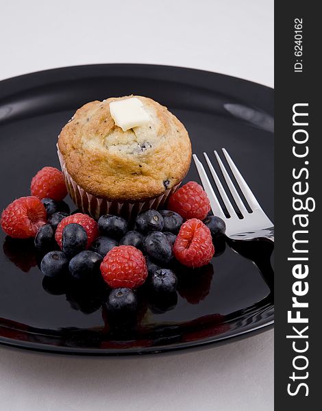 Hot muffins & fresh berries on black plate with fork. Hot muffins & fresh berries on black plate with fork