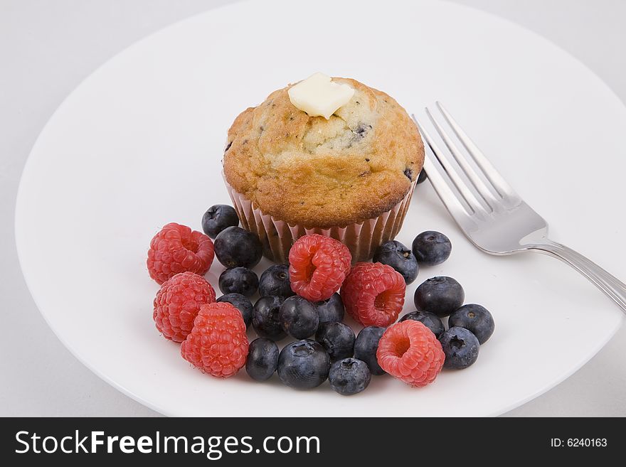 Hot muffins & fresh berries on white plate with fork. Hot muffins & fresh berries on white plate with fork