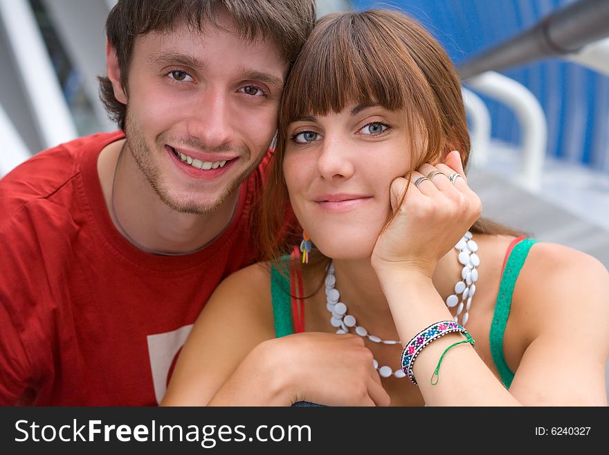 Young smiling teenagers sit together and look towards. Young smiling teenagers sit together and look towards