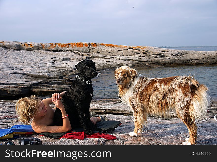 Boy dries off on a rocky shoal after swimming in Georgian bay with the dogs - an Australian Shepperd and Portuguese Water Dog. Boy dries off on a rocky shoal after swimming in Georgian bay with the dogs - an Australian Shepperd and Portuguese Water Dog