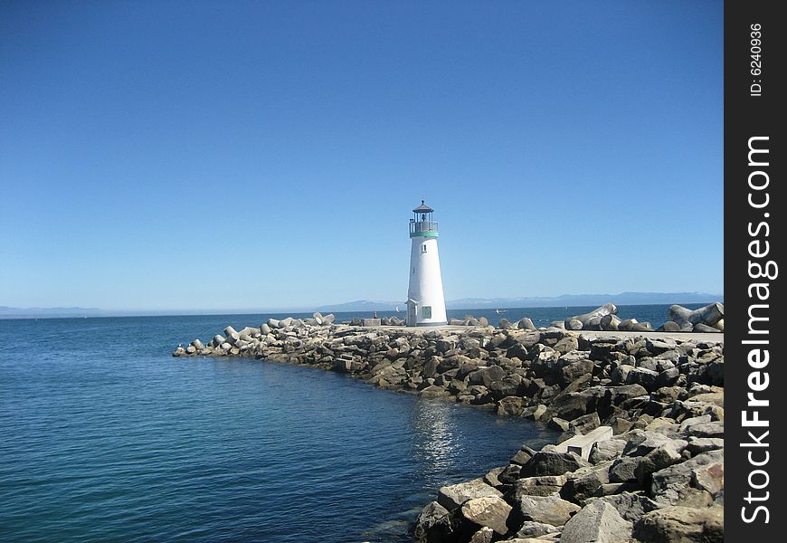 A lighthouse sitting out on a rocky peninsula. A lighthouse sitting out on a rocky peninsula