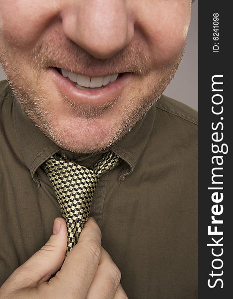 Smiling Man Fixing Tie Against Grey Background