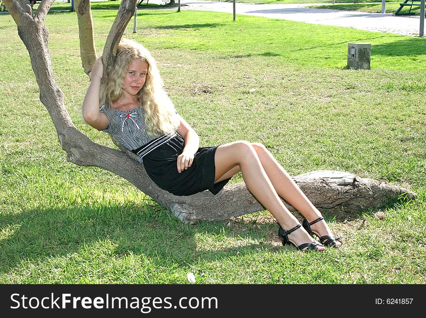 Pretty blond girl with long hair on the tree. Pretty blond girl with long hair on the tree.