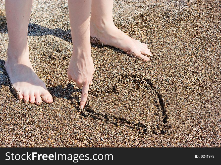 Girl painting heart on the sand