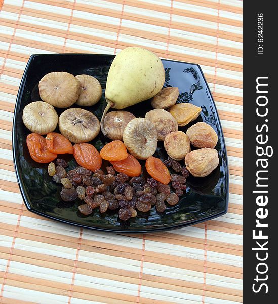 Dry fruit and pear on a black plate