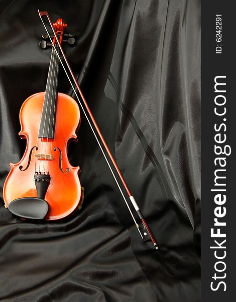 Violin and bow on black silk, music background