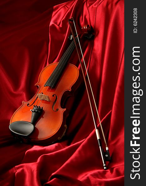 Violin and bow on red silk, music background