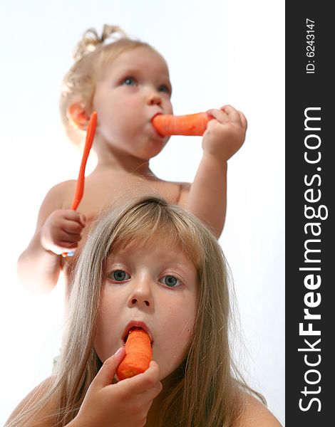 An image of two sisters eating fresh carrot