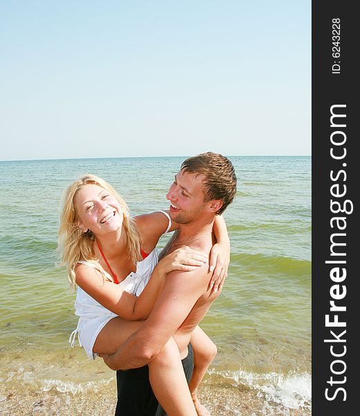 An attractive couple fooling around on the beach, smiling and in love. An attractive couple fooling around on the beach, smiling and in love