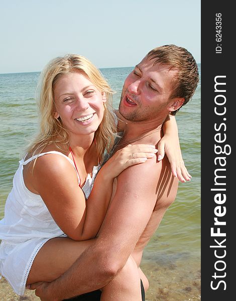 An attractive couple fooling around on the beach, smiling and in love. An attractive couple fooling around on the beach, smiling and in love