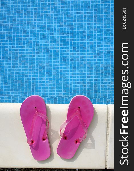 Pink swimming pool sandals on a blue water background