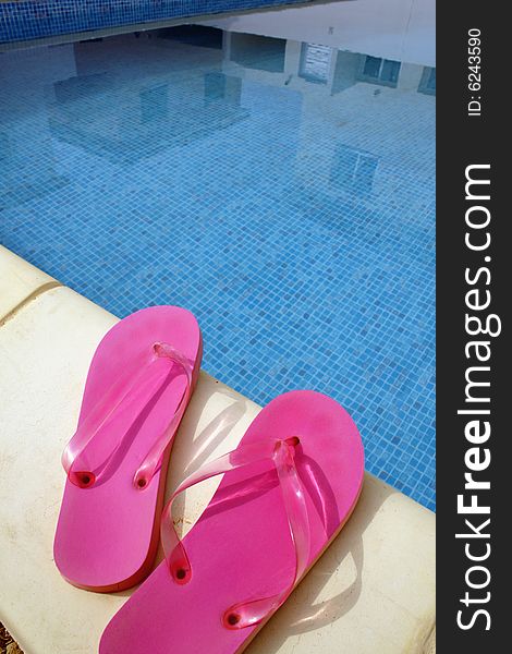 Pink swimming pool sandals on a blue water background