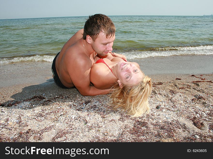 An attractive couple fooling around on the beach, smiling and in love. An attractive couple fooling around on the beach, smiling and in love