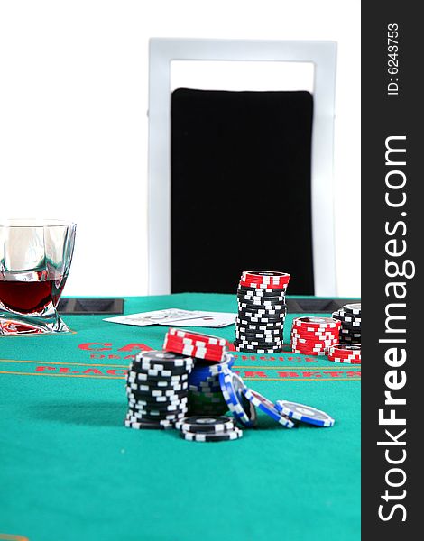 A poker table with chips a drink and cards. A chair invites to sit down. Isolated over white. A poker table with chips a drink and cards. A chair invites to sit down. Isolated over white.