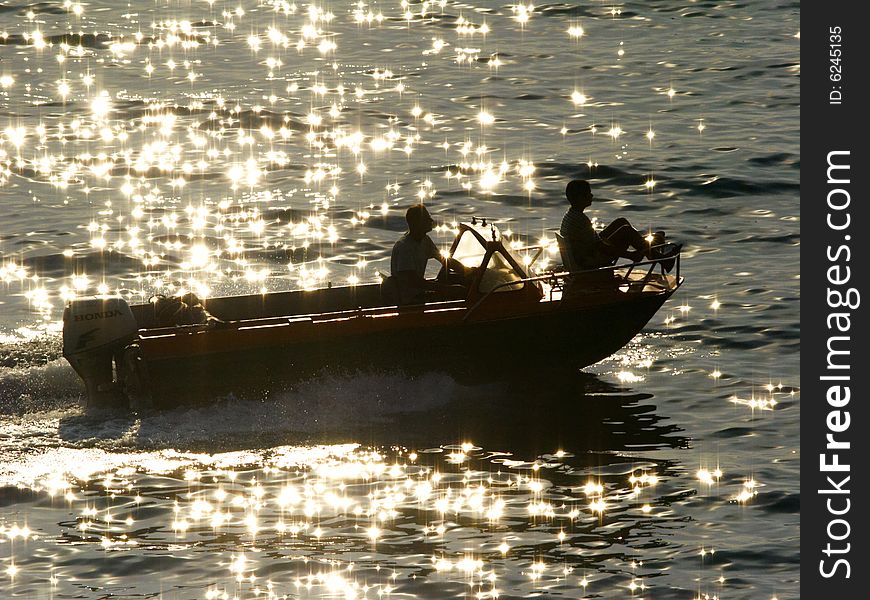 Boat is in the rays of a sun,
boat in the reflections of a sun on water