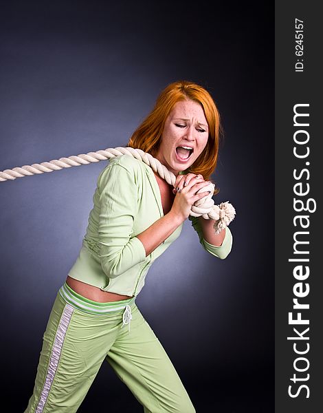 The young woman in a sports suit pulls a rope.