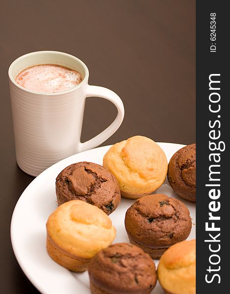 A cup of foaming hot chocolate and chocolate mint and vanilla muffins. A cup of foaming hot chocolate and chocolate mint and vanilla muffins