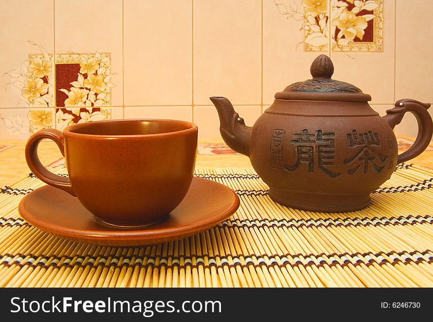 Teapot, cup, saucer on yellow tablecloth. Teapot, cup, saucer on yellow tablecloth