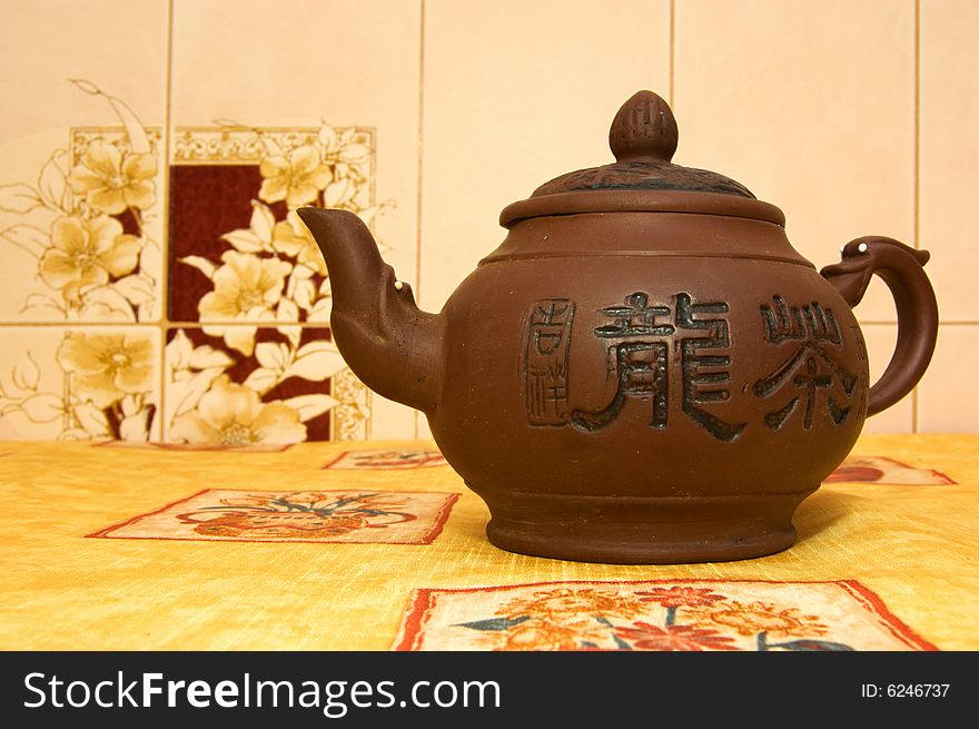 Brown clay teapot on bright yellow tablecloth. Brown clay teapot on bright yellow tablecloth