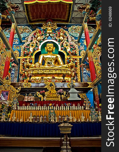 Huge golden colored Budha, in a sitting pose, surrounded by colorful statues in a monastry near Coorg, India. Huge golden colored Budha, in a sitting pose, surrounded by colorful statues in a monastry near Coorg, India