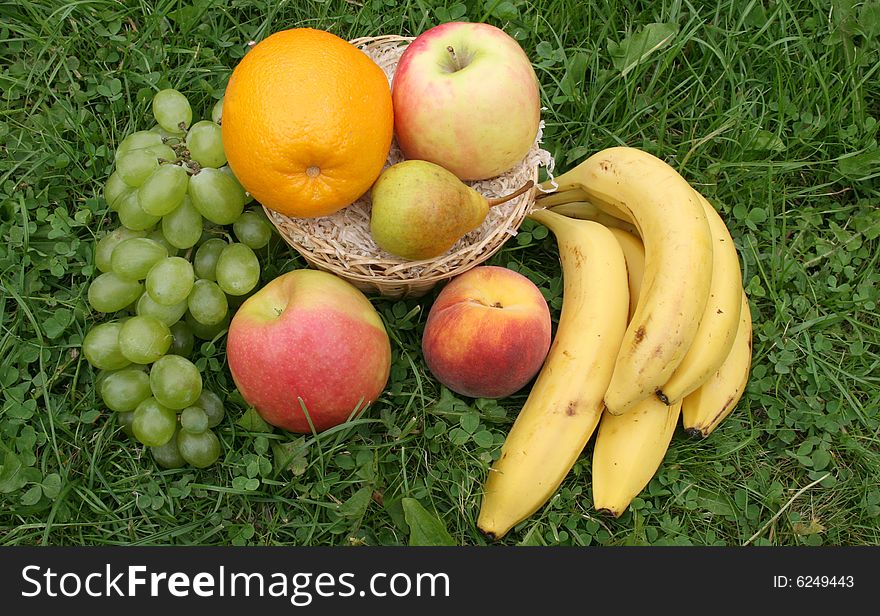 Fruit in a basket in a grass on 
a lawn