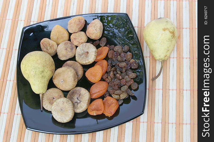 Fruit and pears on a black plate. Fruit and pears on a black plate