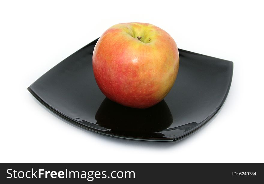Ripe apple on a black plate on a white background