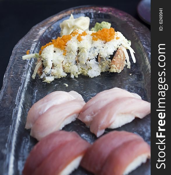 Spicy tuna roll (maki) with flying fish roe (tobiko) garnish on glass serving dish with tuna and yellowtail nigiri sushi. Spicy tuna roll (maki) with flying fish roe (tobiko) garnish on glass serving dish with tuna and yellowtail nigiri sushi